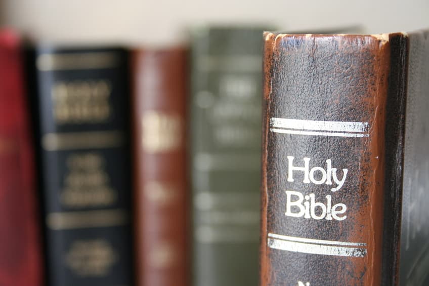 A Holy Bible beside books on a shelf