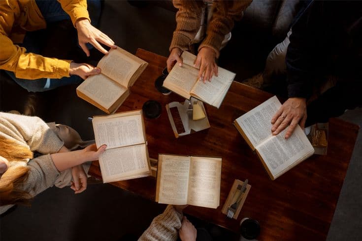People gathered around a table studying open books